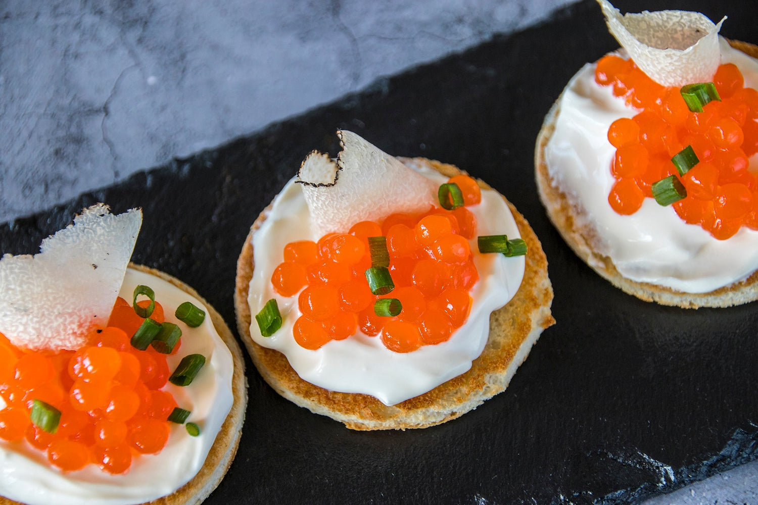 Canapé con creme fraiche, huevas de salmón y trufa de verano