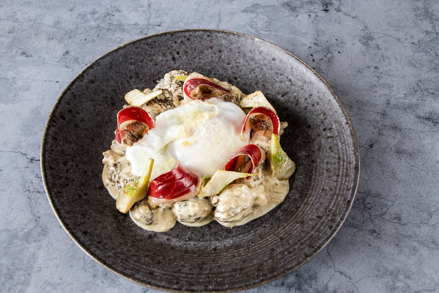 Huevo frito de oca con colmenillas, alcachofas y jamón de pato